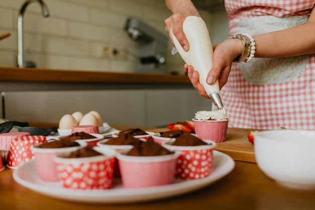 Donna che prepara gustosi cupcake di Pasqua in cucina