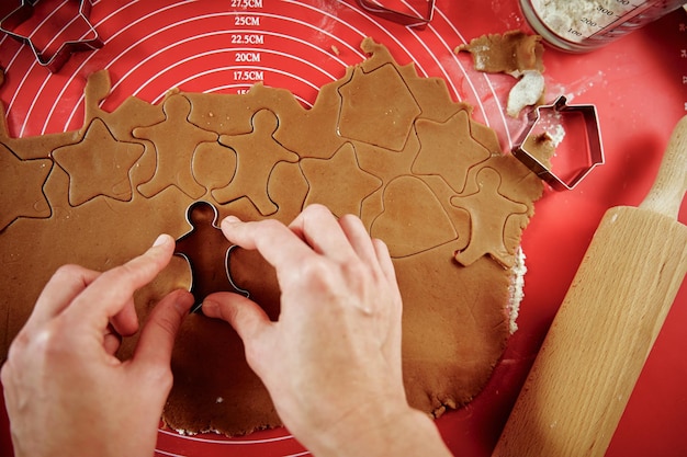 Donna che prepara i biscotti di pan di zenzero in cucina mani femminili che tagliano la pasta allo zenzero con la taglierina per maki