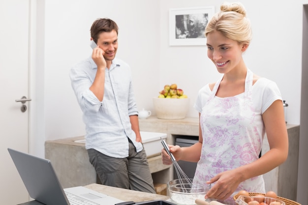 Donna che prepara i biscotti mentre l&#39;uomo della chiamata in cucina