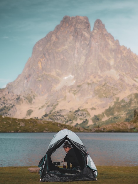 Donna che prepara il cibo al campo vicino al lago contro la montagna rocciosa