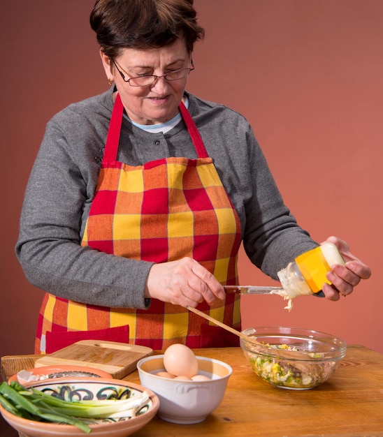 Donna che prepara insalata su sfondo arancione