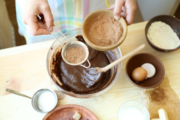 Donna che prepara l'impasto per la torta al cioccolato sul tavolo da vicino