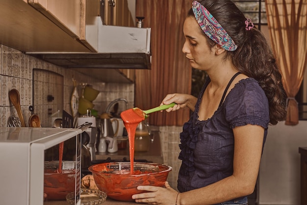 Donna che prepara l'impasto per una torta di velluto rosso