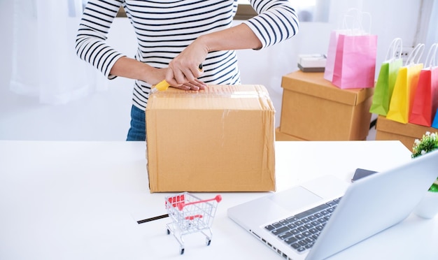 Donna che prepara la scatola di consegna del pacco a casa per lo shopping online