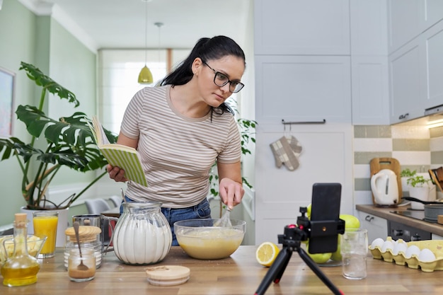 Donna che prepara la torta di mele a casa in cucina parlando online tramite videochiamata