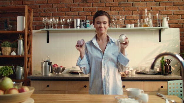 Donna che prepara una sana colazione Ragazza che mette due tazze di yogurt sul tavolo di legno