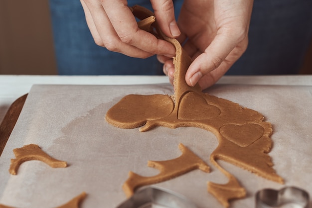 Donna che produce i biscotti a forma di cuore del pan di zenzero