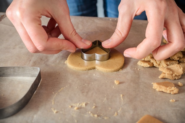 Donna che produce i biscotti fatti in casa allo zenzero a forma di cuori su un tavolo di legno.