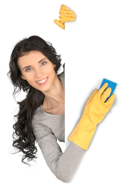 Donna che pulisce un muro bianco con guanti e spugna