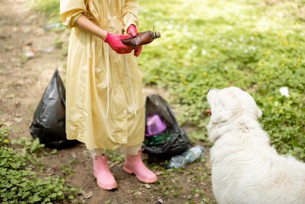 Donna che raccoglie rifiuti di plastica sparsi nei boschi