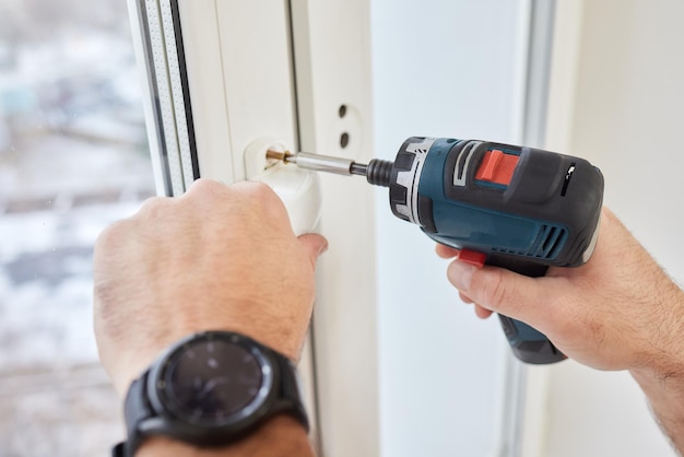 Donna che regola la porta della finestra del balcone in plastica bianca in pvc al chiuso femmina utilizzando un cacciavite per riparare la serratura della finestra in upvc porte e finestre della casa concetto di manutenzione progetto di fissaggio concettuale