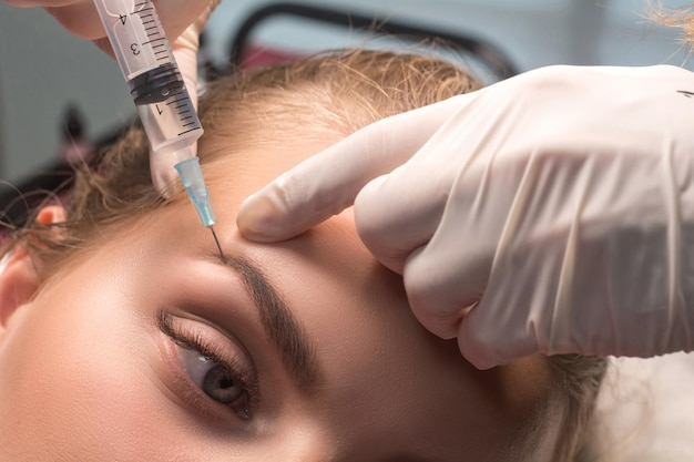 Donna che riceve un'iniezione cosmetica di botulino vicino agli occhi Rughe dei piedi di gallina Mesoterapia del sopracciglio