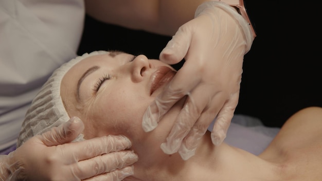 Donna che riceve un massaggio facciale antietà nel salone spa relax Benessere corpo cura della pelle viso trattamento di bellezza Sfondo nero