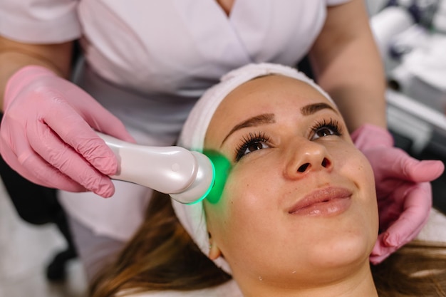 Donna che riceve un trattamento viso laser e ad ultrasuoni nel concetto di ringiovanimento della pelle del centro termale medico