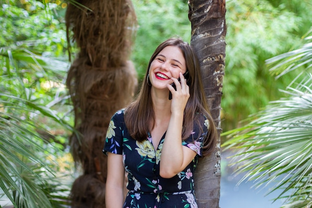 Donna che ride e che parla sullo smartphone in parco