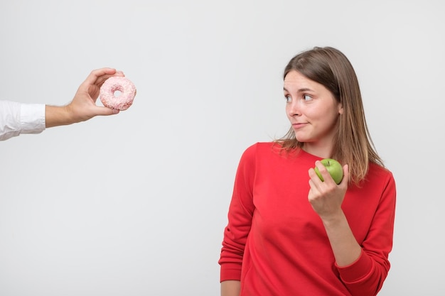 Donna che rifiuta la ciambella o il dessert e sceglie cibo sano