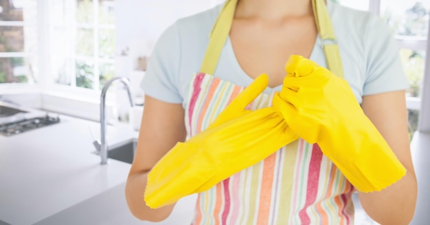 Donna che rimuove i guanti di gomma in cucina