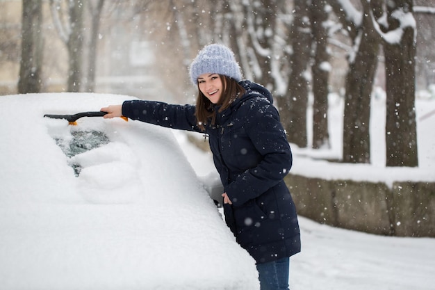 Donna che rimuove la neve dal parabrezza dell'auto