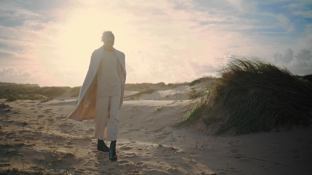 Donna che riposa sulle dune di sabbia che posa alla luce del sole elegante afroamericana che ammira