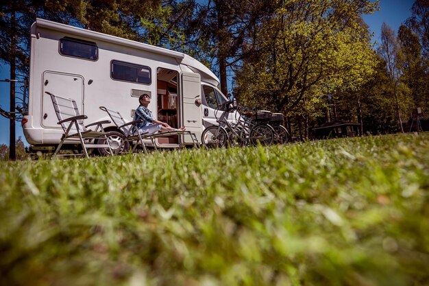 Donna che riposa vicino ai camper in natura. Viaggio di vacanza in famiglia, viaggio di vacanza in camper, vacanza in caravan.