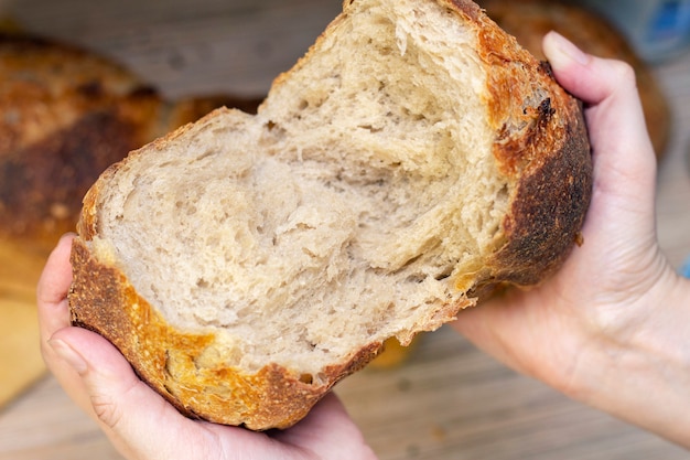 Donna che rompe pane fresco, primo piano. Pane tradizionale fresco aromatizzato. Concetto di cibo.