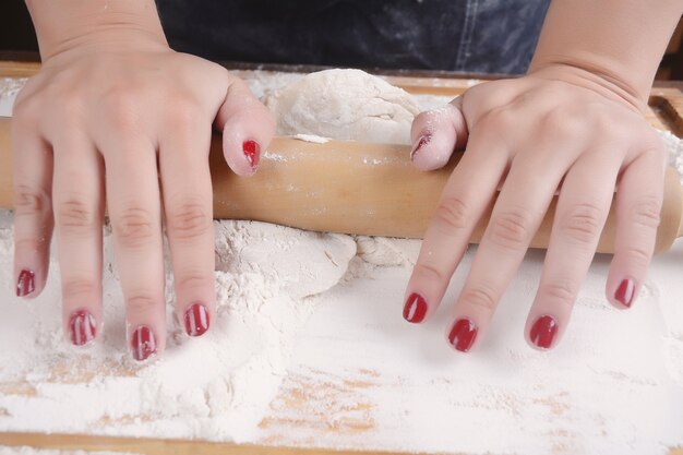 Donna che rotola la pasta con il matterello.