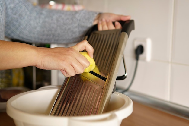 Donna che sbuccia le patate con un pelapatate nella sua cucina