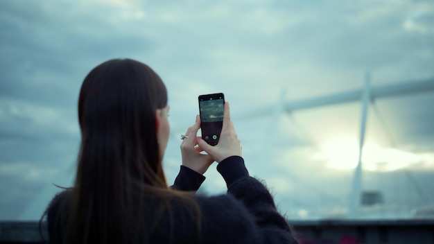 Donna che scatta foto sul cellulare in strada Ragazza bruna che utilizza smartphone