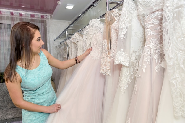 Donna che sceglie l'abito da sposa bianco nel negozio della sposa