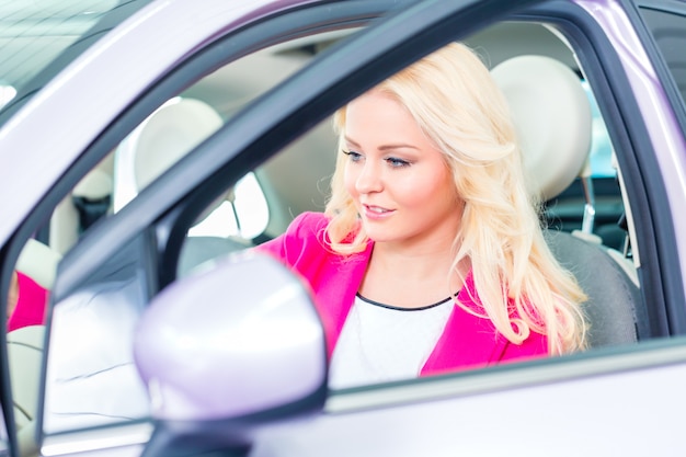 Donna che sceglie l&#39;automobile per l&#39;acquisto nella gestione commerciale