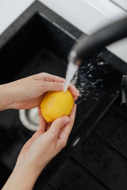 Donna che sciacqua un limone giallo in un lavandino