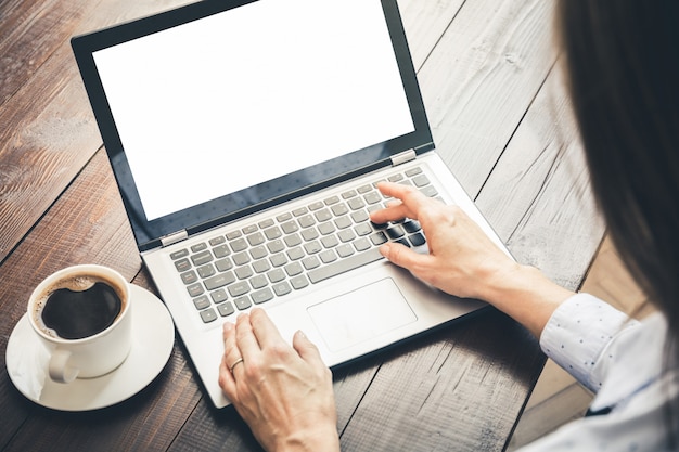 Donna che scrive e che cerca dal computer portatile in ufficio. Spazio nella schermata per il testo.