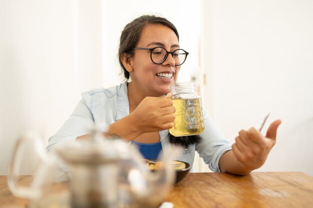 Donna che scrive messaggi mentre fa colazione con frutta e sorride