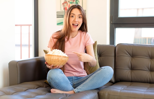 Donna che sembra eccitata e sorpresa che punta di lato e verso l'alto per copiare lo spazio