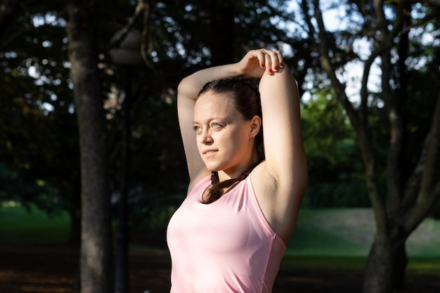 Donna che si allunga per riscaldarsi prima di correre o allenarsi nel parco in autunno Concetto di fitness e stile di vita sano