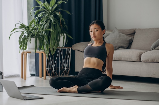 Donna che si allunga sul tappetino da yoga a casa