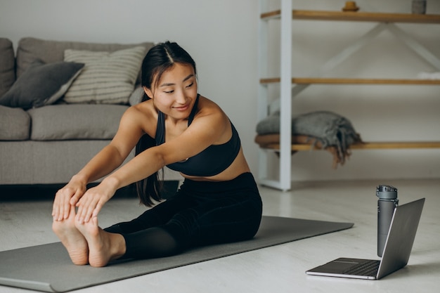 Donna che si allunga sul tappetino da yoga a casa