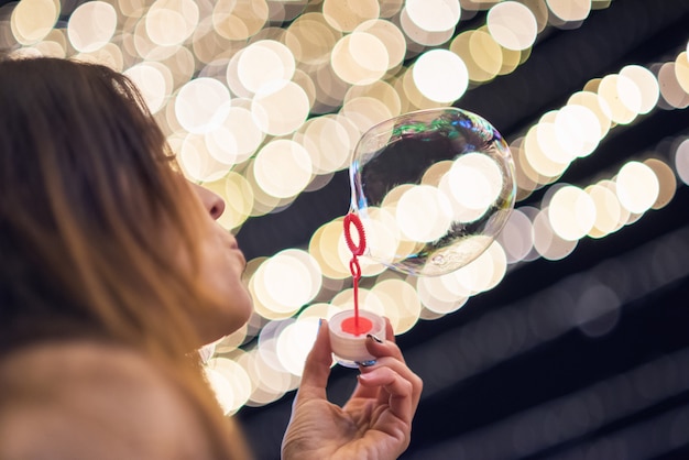 Donna che si diverte a fare bolle di sapone durante la festa di notte o la vigilia di Capodanno