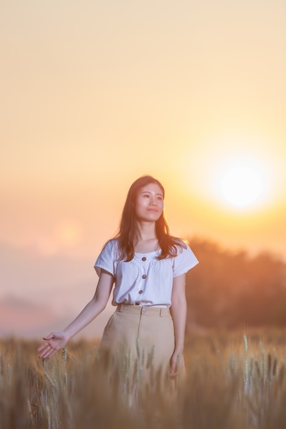 donna che si diverte al campo di orzo al momento del tramonto