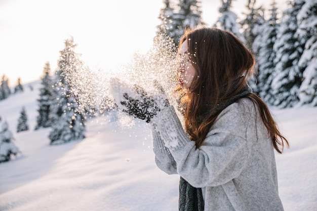 Donna che si diverte mentre fa un'escursione nella neve durante l'inverno al tramonto.