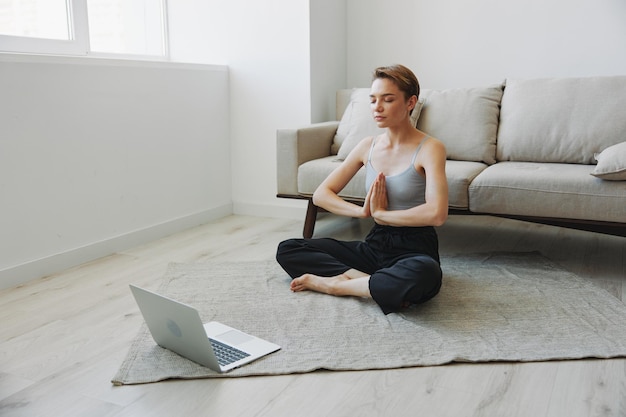 Donna che si esercita a casa con la meditazione online di allenamento video e allunga la salute mentale