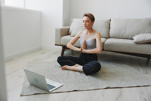 Donna che si esercita a casa con la meditazione online di allenamento video e allunga la salute mentale