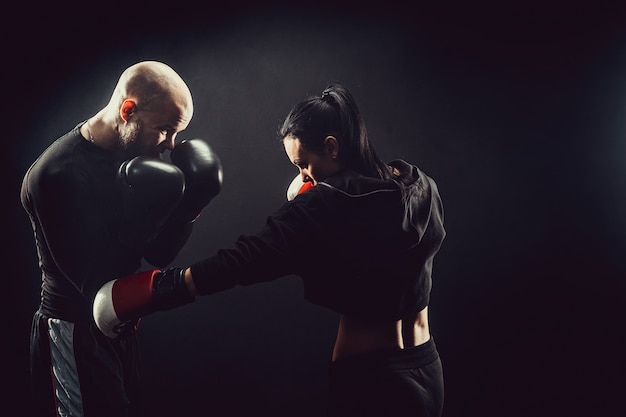 Donna che si esercita con il trainer alla lezione di boxe e autodifesa