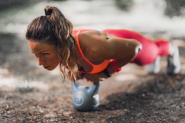 Donna che si esercita con Kettlebell all'aperto nel parco pubblico