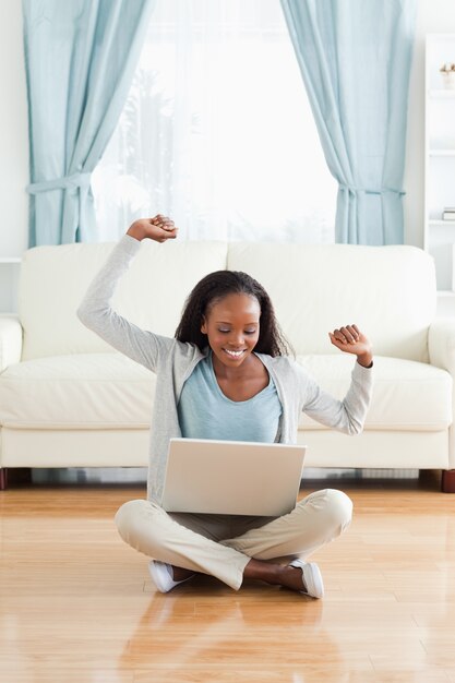 Donna che si estende mentre seduto sul pavimento con il notebook