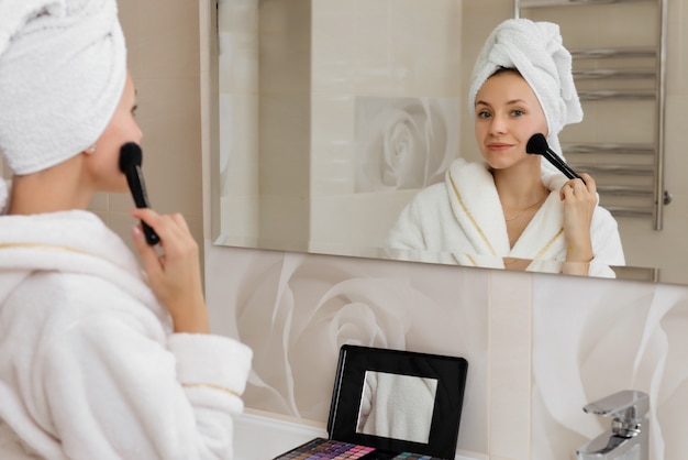 Donna che si fa il trucco a casa in bagno