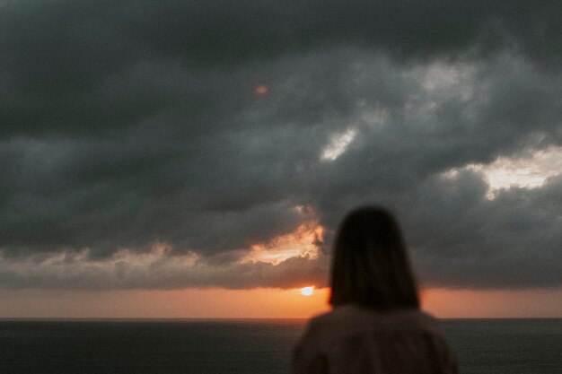 Donna che si gode l'alba su una scogliera in spiaggia