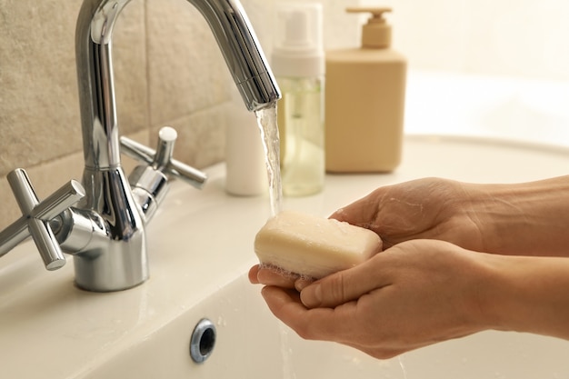 Donna che si lava le mani nel lavandino del bagno con sapone