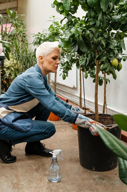 Donna che si prende cura delle piante Giardiniere femminile con piante all'interno