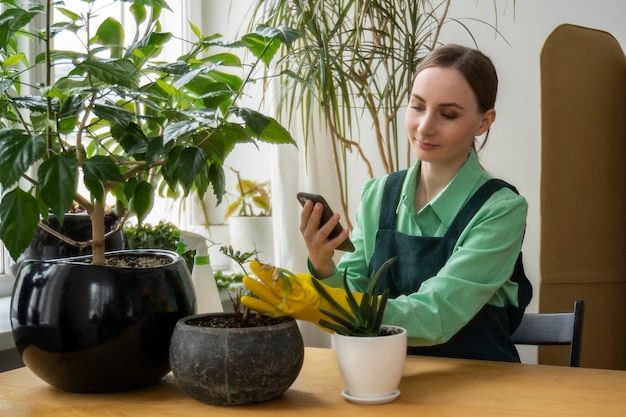 Donna che si prende cura delle sue piante e usa il suo smartphone